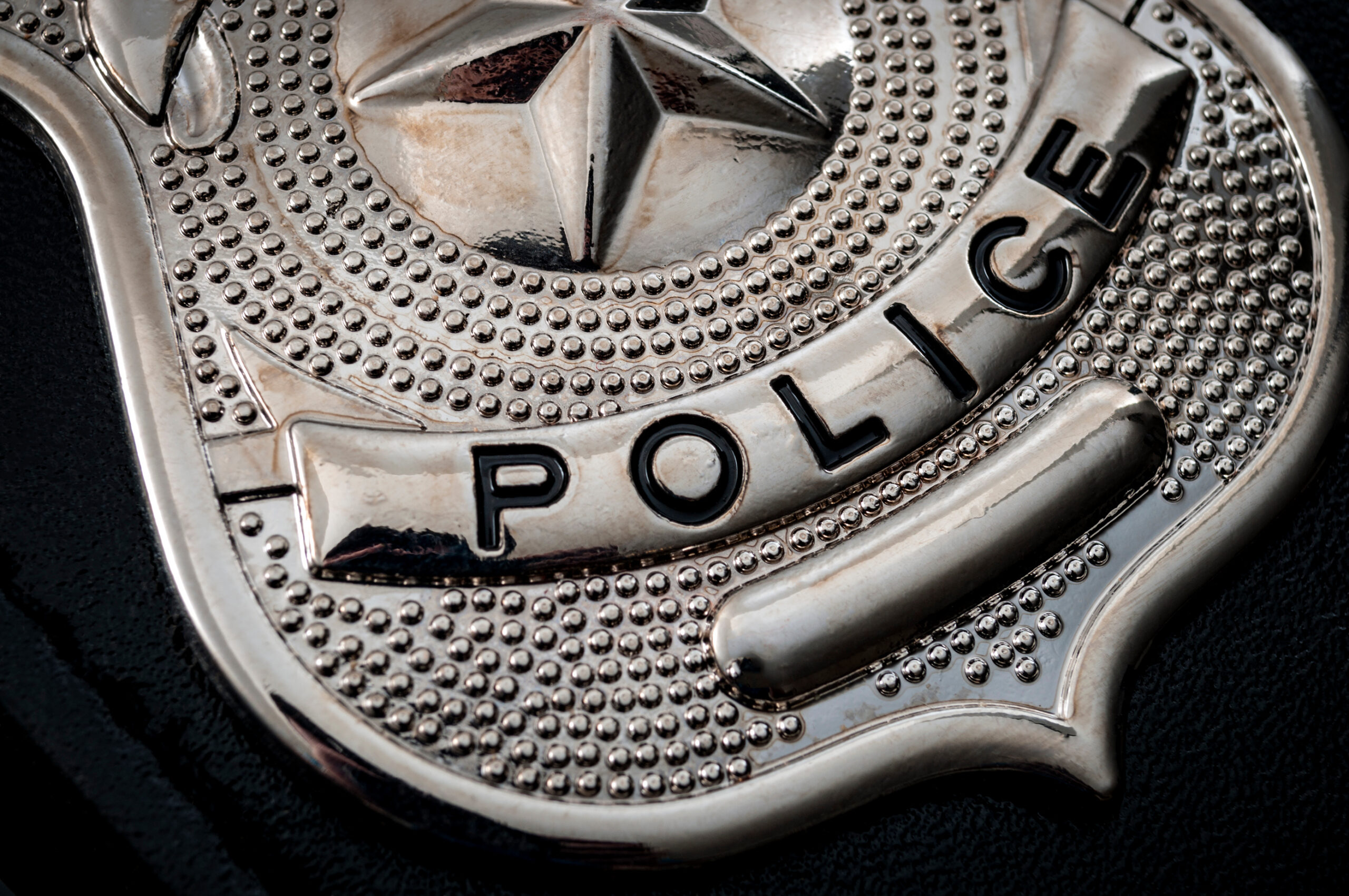 A close-up of a silver police badge lying on a table