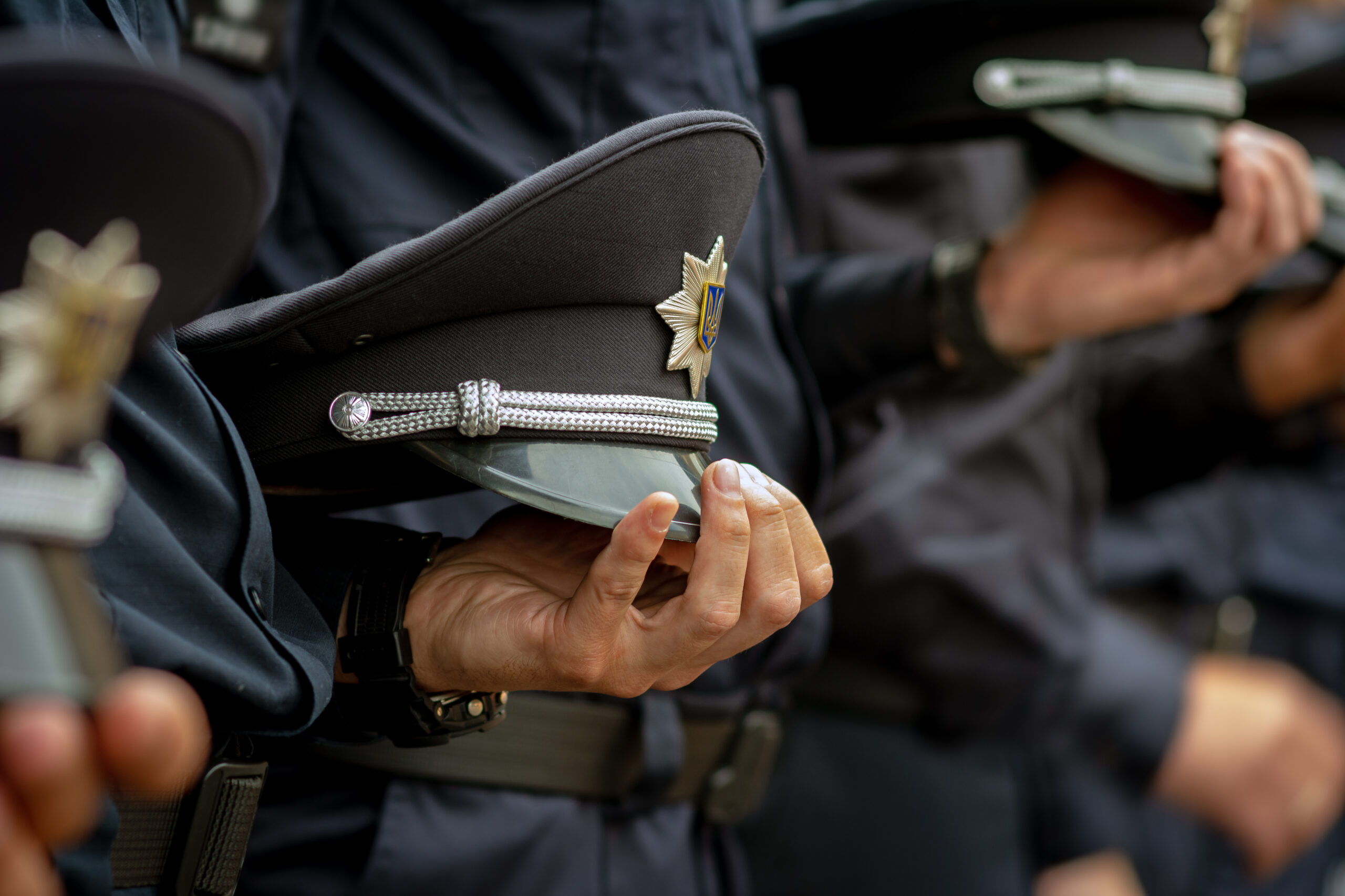 A police officer holding his cap alongside other officers at a ceremony