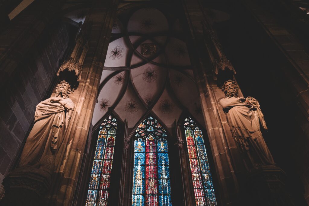 Looking up at large stained glass windows inside of a church