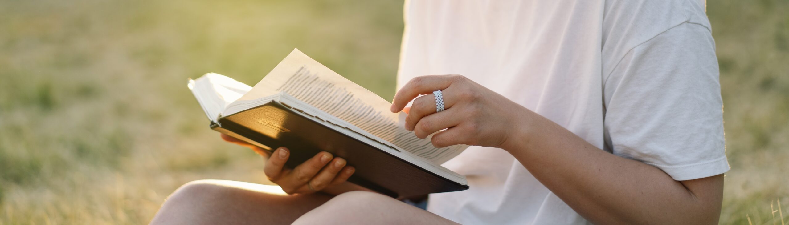 Hands with rings holding a bible and turning the page